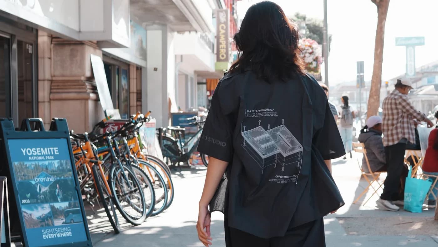 The 2026 EO uniform from behind on a San Francisco street, exploded-view print across the back