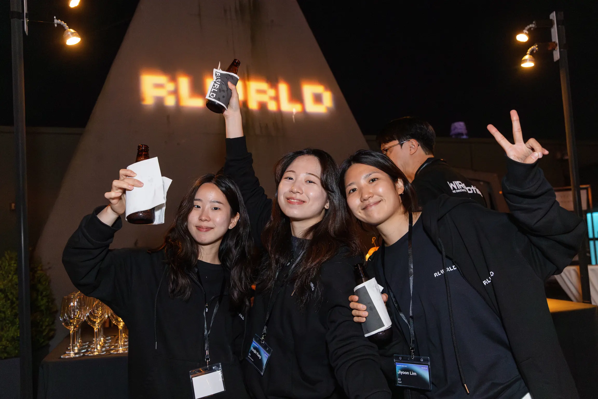 RLWRLD projected large at night, the team below