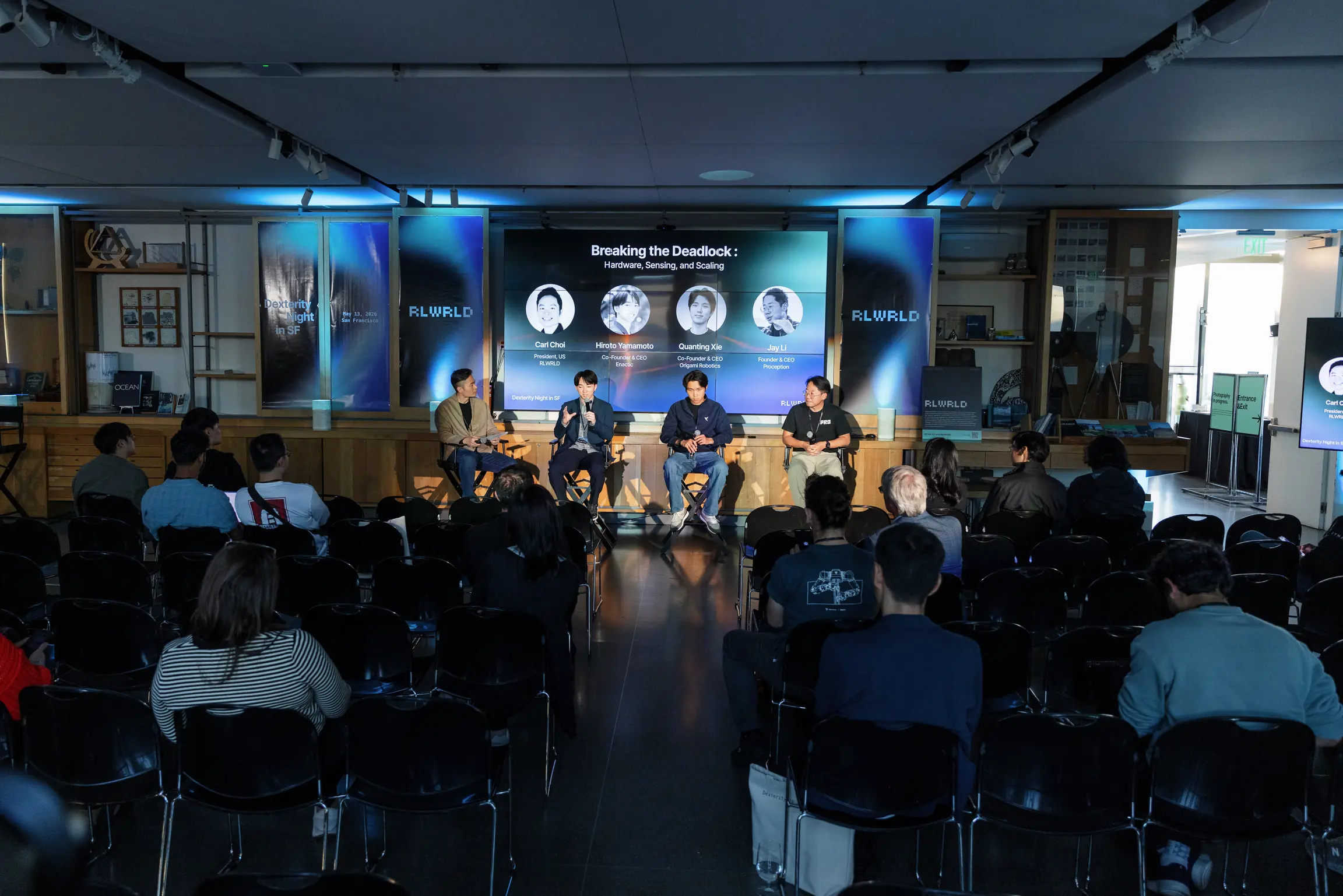 Panel wide at Dexterity Night: ‘Breaking the Deadlock’ on the screen, RLWRLD stage banners, full audience